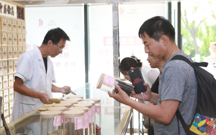 圖為與會(huì)代表在漱玉平民大藥房（西門店）調(diào)研學(xué)習(xí)，了解執(zhí)業(yè)藥師在藥店開展藥學(xué)服務(wù)情況。